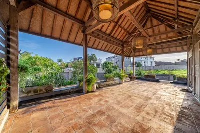an outdoor patio with a wooden roof with potted plants at Villa Ayuni, Berawa in Canggu
