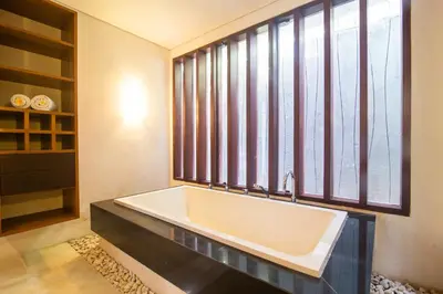 a large bath tub in a bathroom with windows at Rekso Villa in Jimbaran
