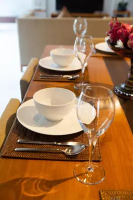 a wooden table with plates and wine glasses on it at Rekso Villa in Jimbaran