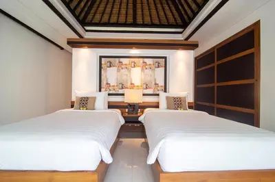 a bedroom with two beds and a painting on the wall at Rekso Villa in Jimbaran