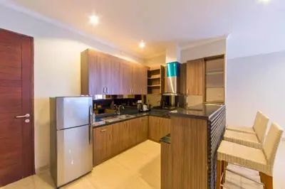 a kitchen with wooden cabinets and a stainless steel refrigerator at Entire 3 BR Private Pool Villa in Seminyak