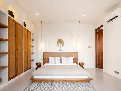 a bedroom with a white bed and wooden cabinets at Casa Pelagos in Kerobokan