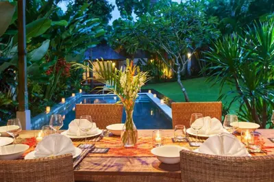 a wooden table with chairs and a table set for a meal at Clover 3 BR Private Pool Villa in Canggu