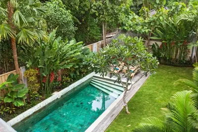 a swimming pool in the middle of a garden at Clover 3 BR Private Pool Villa in Canggu