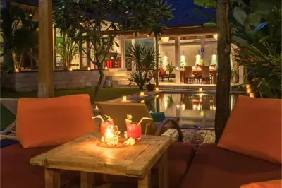 a table with two chairs and a pool at night at Clover 3 BR Private Pool Villa in Canggu
