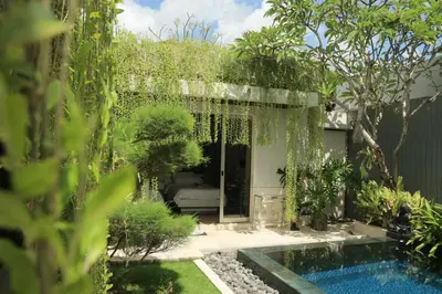 a garden with a swimming pool and trees at Vlad Bali Villa in Jimbaran