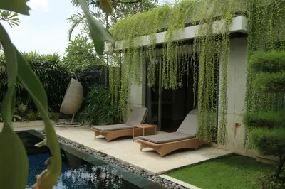a garden with two chairs and a swimming pool at Vlad Bali Villa in Jimbaran