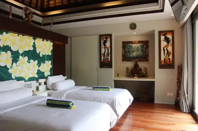 a bedroom with two beds and a painting on the wall at Vlad Bali Villa in Jimbaran
