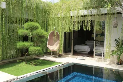 a garden with a swimming pool next to a house at Vlad Bali Villa in Jimbaran
