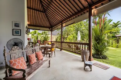 a porch with a wooden bench and a table at Villa Kuda Sumba by BaliSuperHost in Kerobokan