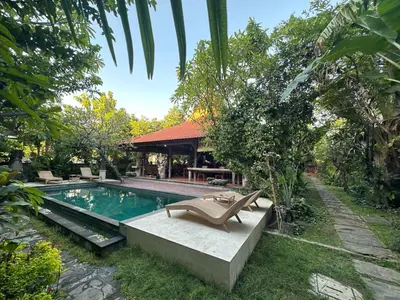 a pool with two lounge chairs next to a house at Bali Telaga Hati Yoga Healing and Retreat Center Villa in Sanur
