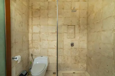 a bathroom with a toilet and a glass shower at Ocean Breeze Villa -4BR villa in Canggu in Canggu