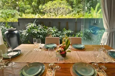 a wooden table with plates and wine glasses on it at Kamila Aranne 3 BR Private Pool Villa in Jimbaran