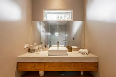 a bathroom with a sink and a large mirror at Stylish 1 Bd Pvt Apartment w shared kitchen and pool in Seminyak