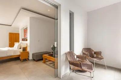 a living room with two chairs and a bedroom at Stylish 1 Bd Pvt Apartment w shared kitchen and pool in Seminyak