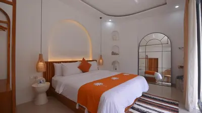 a bedroom with a large bed with an orange blanket at Queen Villa Seminyak in Seminyak