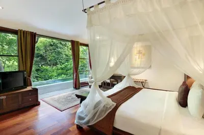 a bedroom with a bed and a tv and windows at Ari Ayra 1 BR Private Pool Villa in Jimbaran