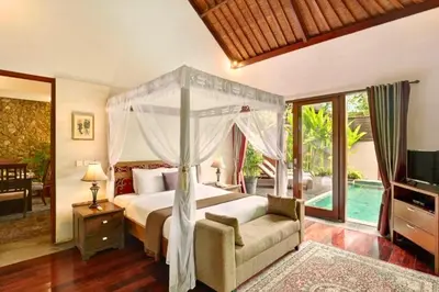 a bedroom with a canopy bed and a couch and a television at Ari Ayra 1 BR Private Pool Villa in Jimbaran