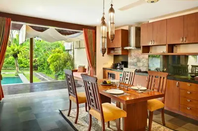 a kitchen with a wooden table and chairs and a dining room at Dean 2 BR Private Pool Villa in Jimbaran