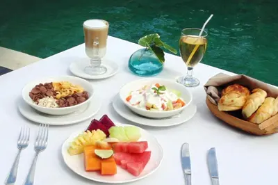 a table with plates of food and glasses of wine at Azarina 3 BR Private Pool Villa in Jimbaran