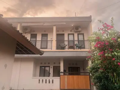 a white house with a balcony with chairs on it at Conscious House near Kuta and Seminyak in Legian