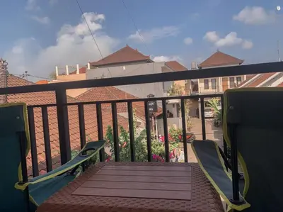 a balcony with two chairs and a view of a house at Conscious House near Kuta and Seminyak in Legian