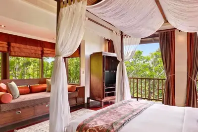 a bedroom with a canopy bed and a balcony at Dendalion 4 BR Private Pool Villa in Jimbaran