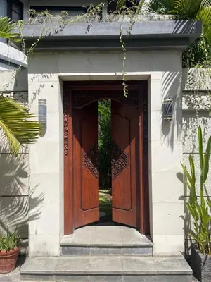 a large wooden door on a building with plants at Langikula Villa Seminyak Bali in Seminyak