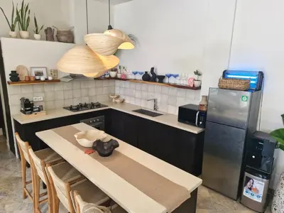 a kitchen with a table and a refrigerator at Langikula Villa Seminyak Bali in Seminyak