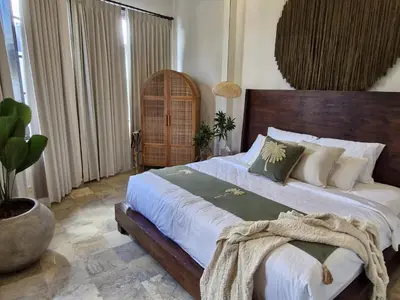 a bedroom with a large bed with white sheets and pillows at Langikula Villa Seminyak Bali in Seminyak