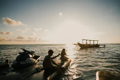 three people sitting on a raft in the water with a boat at Floating Hotel SALTWATER COWBOYS in Kuta