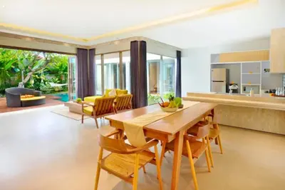 a kitchen and living room with a wooden table and chairs at Sweet 3 BR Private Pool Villa Garden View in Kerobokan