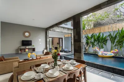 a dining room with a table and a swimming pool at Taman Bali Villa Kerobokan in Kerobokan