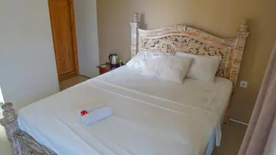 a bedroom with a white bed with a roll on it at Dirga's House Sanur View by EPS in Sanur