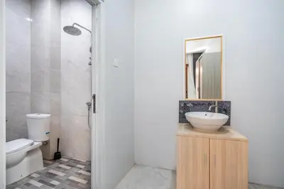 a bathroom with a sink and a toilet and a mirror at Dukuh Segara Guest House in Legian