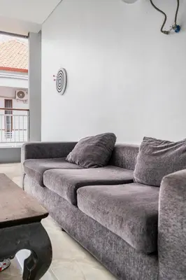 a gray couch in a living room with a table at Dukuh Segara Guest House in Legian