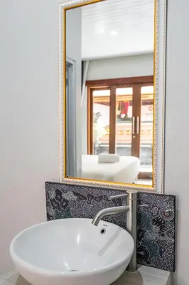 a bathroom with a white sink and a mirror at Dukuh Segara Guest House in Legian