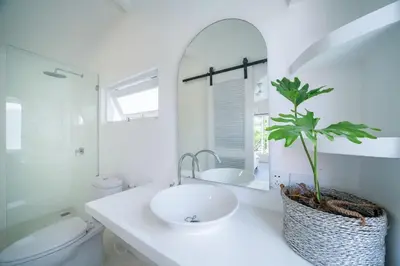 a bathroom with a sink and a toilet and a mirror at Lovely 3 BR villa with private pool in Canggu
