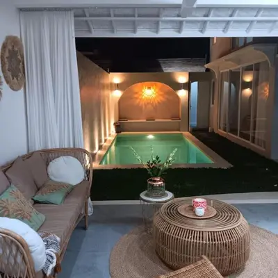 a pool in a room with a couch and a table at Lovely 3 BR villa with private pool in Canggu