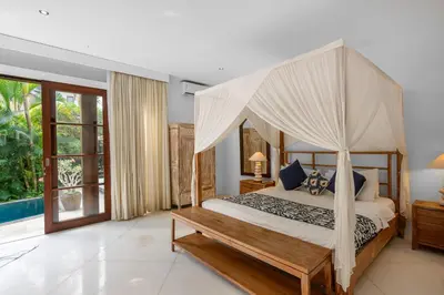 a bedroom with a canopy bed and a pool at Sahaja Villa by Betterplace in Canggu