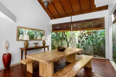 a dining room with a wooden table and benches at Sahaja Villa by Betterplace in Canggu