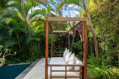 a bed in a wooden swing in a garden at Sahaja Villa by Betterplace in Canggu