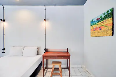 a bed and a table with a stool next to it at Collection O at Jalan Padma near Legian Beach in Legian