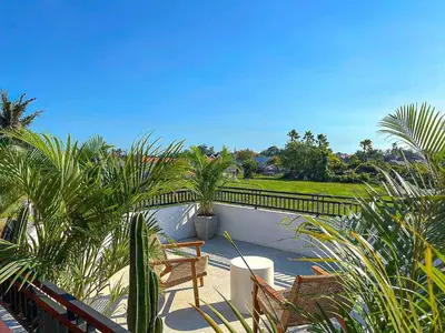 a patio with chairs and palm trees and a fence at Aleksa - Villa with Rooftop&Rice Field View in Canggu