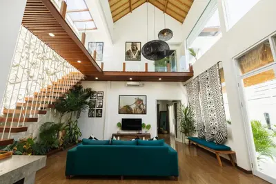 a living room with a blue couch and stairs at Villa Karibu Canggu-2BR with pool & rooftop in Canggu
