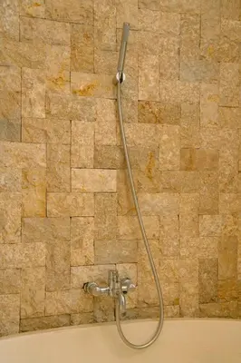 a shower in a bathroom with a stone wall at Villa Chloe by Pertama Management in Seminyak
