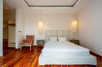 a bedroom with a large white bed and a chair at Villa Chloe by Pertama Management in Seminyak