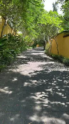 a brick path with trees and a building at Jimbaran Cozy Stay in Jimbaran