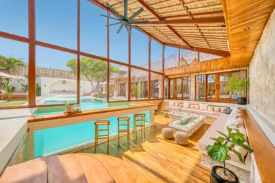 an indoor pool with a bar and stools in a house at Villa Vienna - New 8BDR Jacuzzi Sauna and Cinema in Seminyak