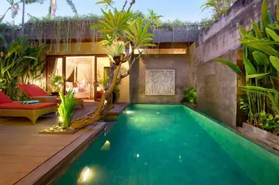 an infinity pool in a backyard with palm trees at Amani Entire 2 BR Private Pool Villa in Seminyak